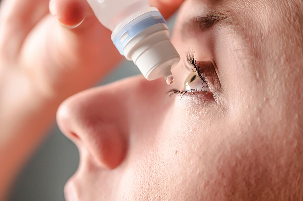 Applying eye drops to soothe irritation, a close-up of a person’s eye and hand demonstrates proper technique for eye care.