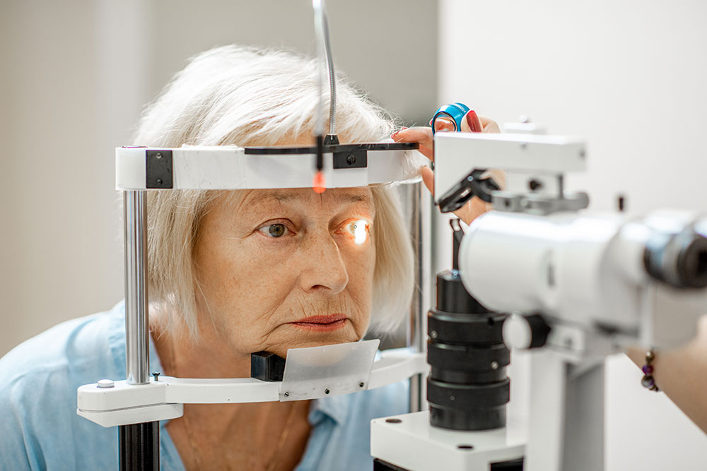 An older woman undergoing an eye examination, focused as she looks into an optical device. The setting highlights the importance of eye health.